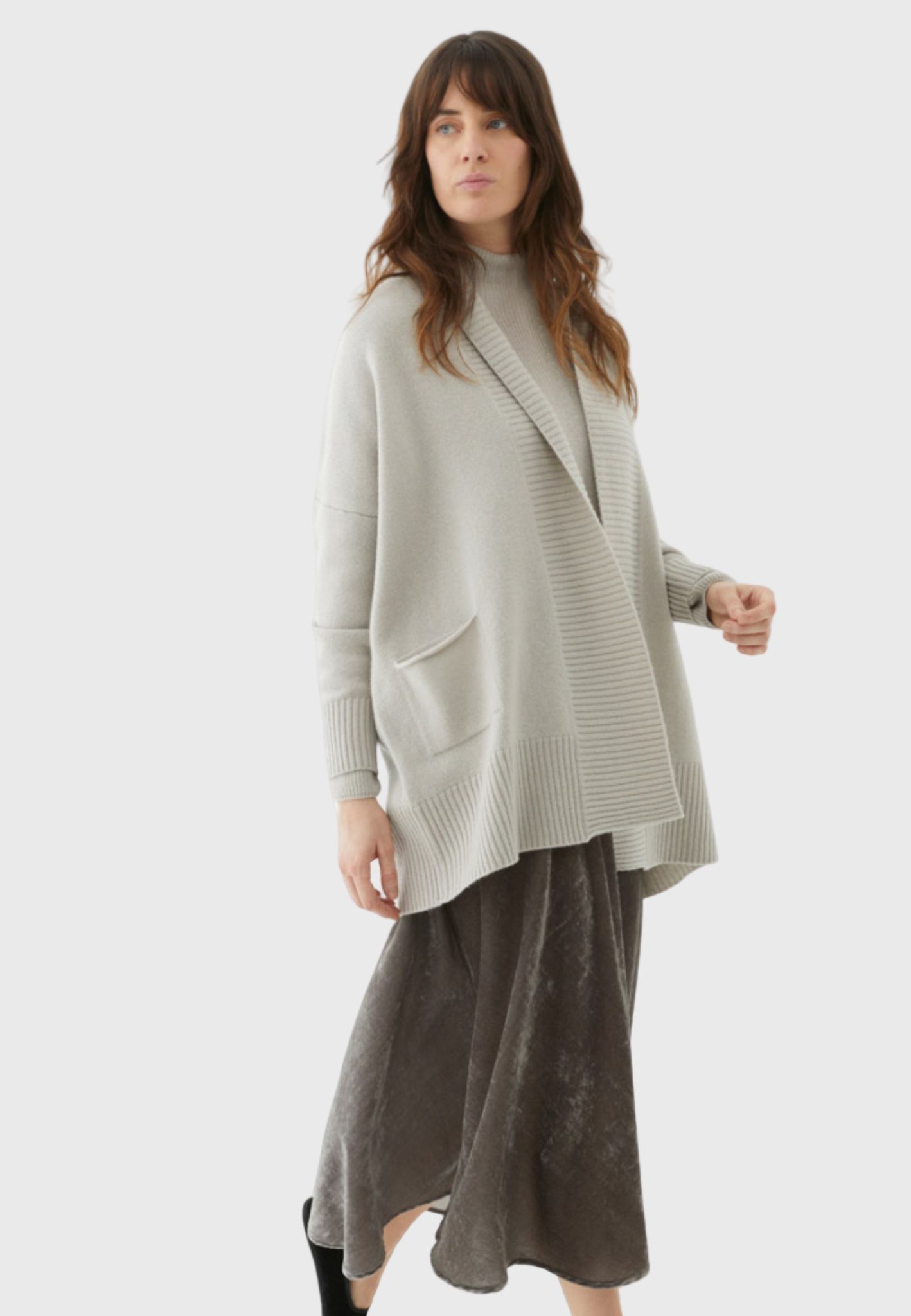 A woman wearing a long cardigan in a stone color, paired with a maxi dress.