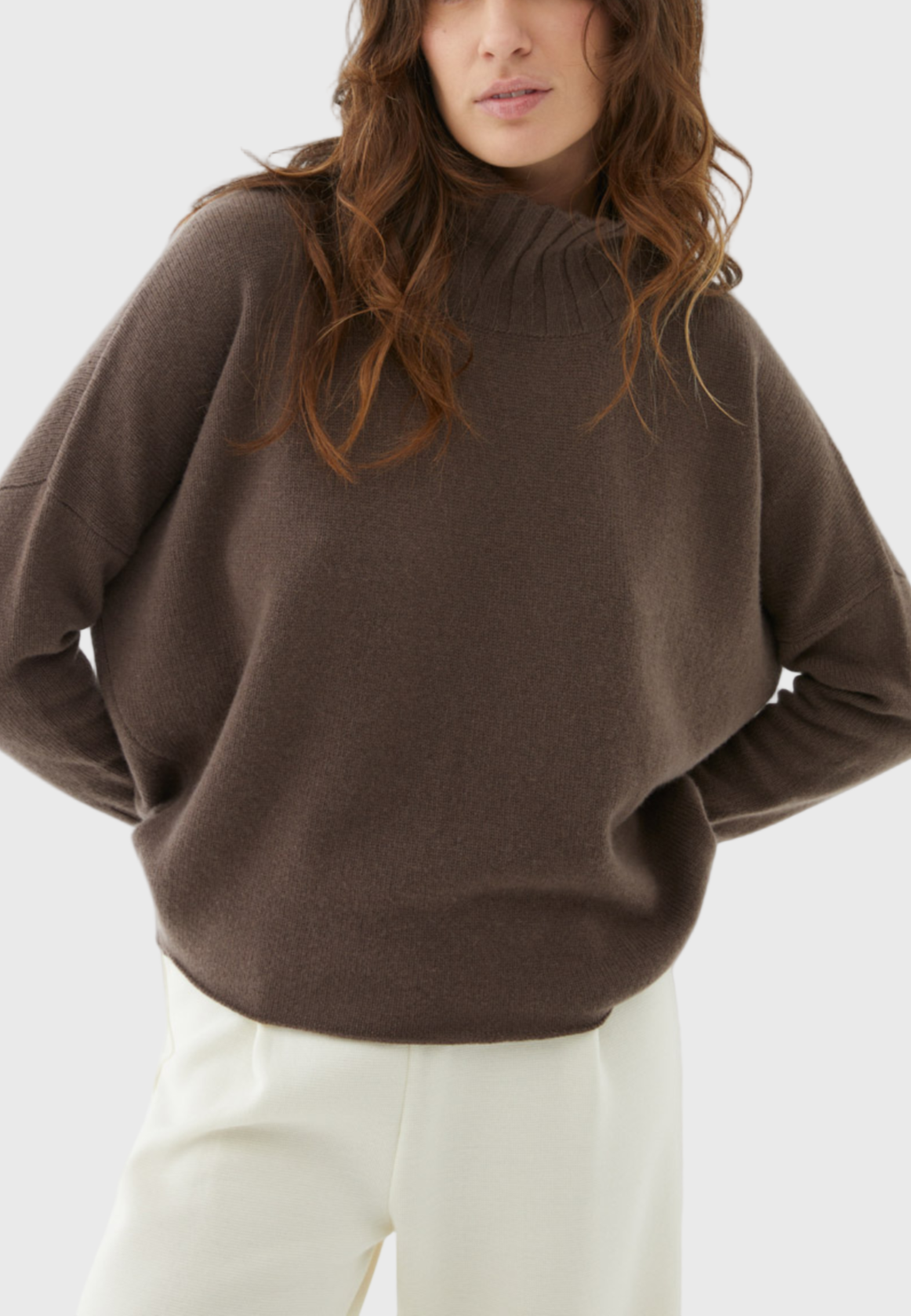 A female model wearing an oversized cashmere sweater in a glacé hue with a relaxed fit.